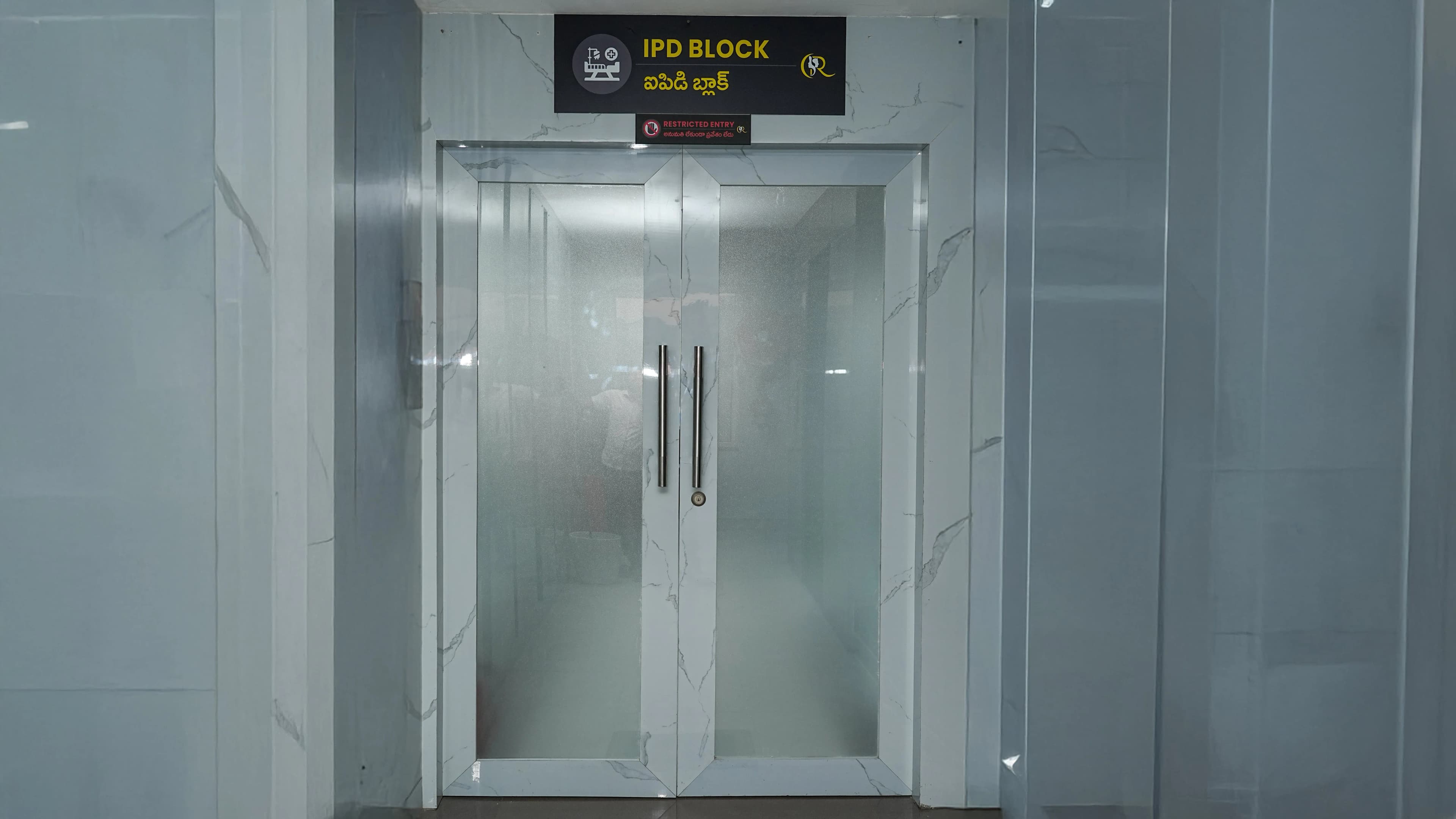 Secure entrance to the Inpatient Department (IPD) block with frosted glass double doors and restricted entry signage