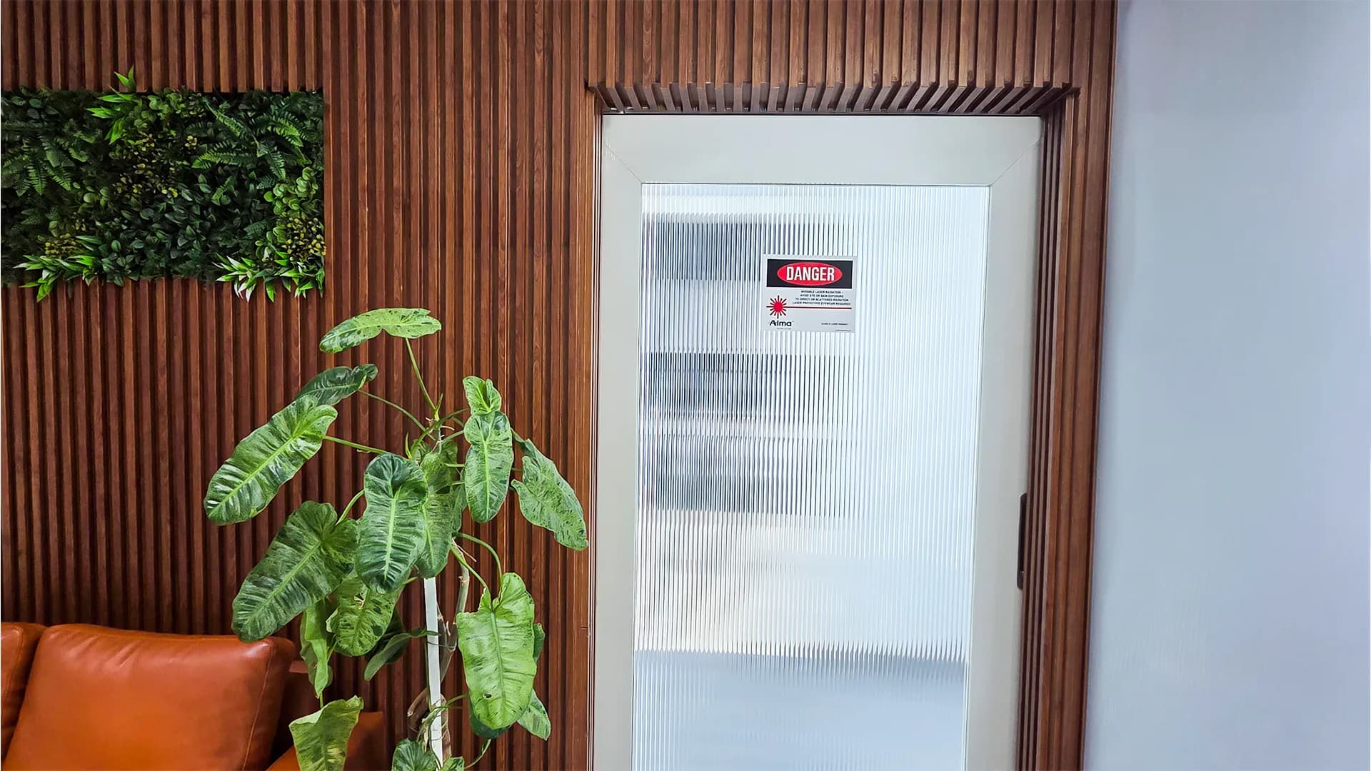 Secure entry door to Laser and Procedure rooms with safety danger signage and wood paneling