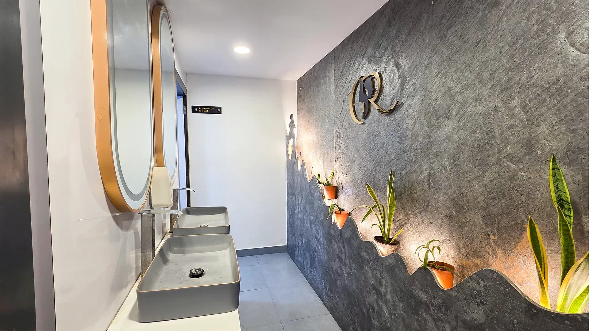 Luxury gender-neutral washroom with stone cladding and sensor taps