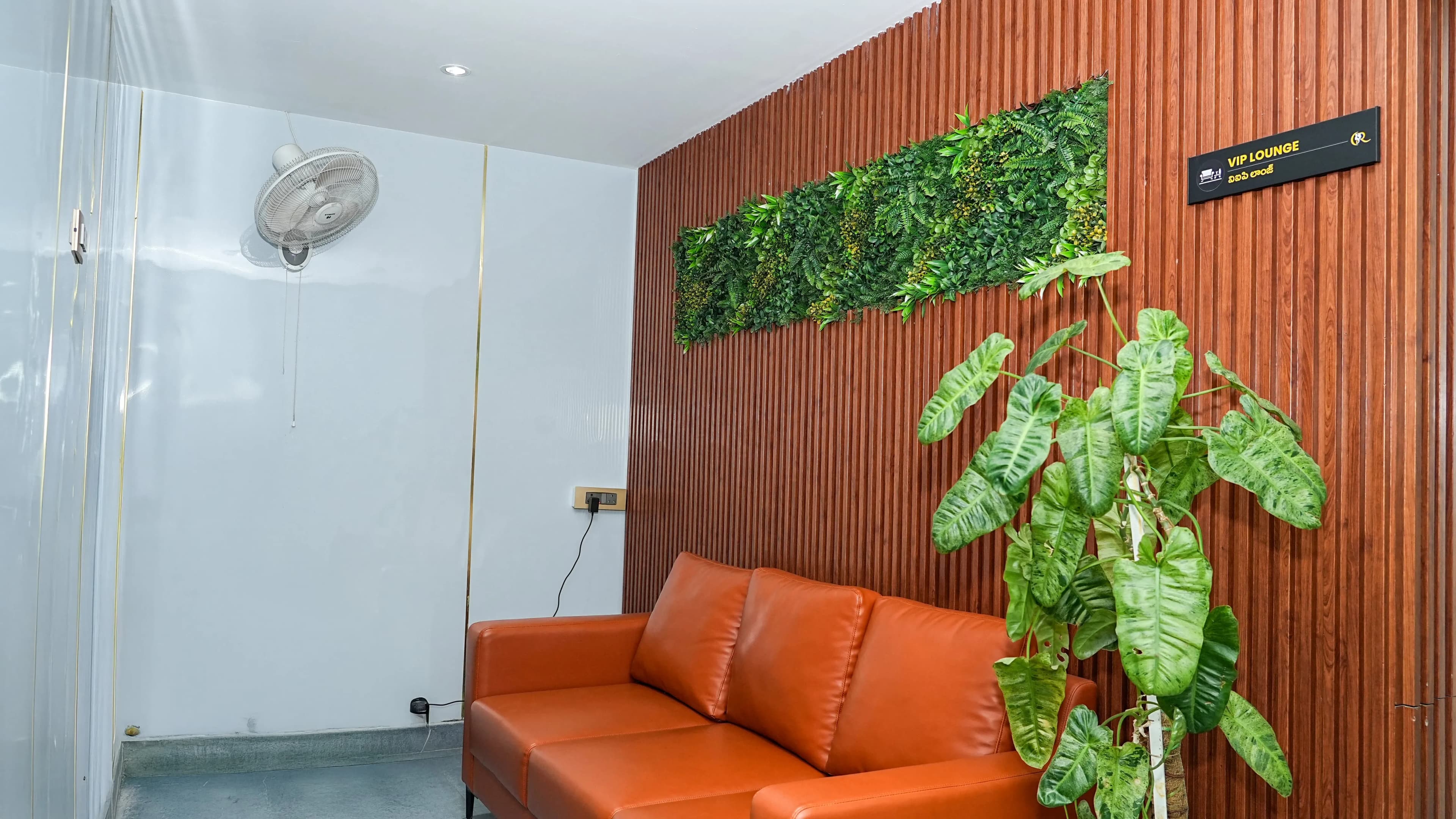 VIP Waiting Lounge at Cosmo Radiance featuring plush orange leather seating and a lush vertical garden wall
